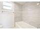 Bathroom featuring a white tub with neutral-colored tiling and a window for natural light at 6304 Memorial Hwy, Tampa, FL 33615