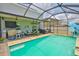 Backyard screened pool with outdoor lounge seating and covered patio with ceiling fans and television at 6512 Trent Creek Dr, Sun City Center, FL 33573