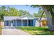 Charming single-story home showcasing a covered carport, blue exterior, and well-maintained front yard, complemented by lush greenery at 7065 73Rd N St, Pinellas Park, FL 33781