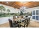 Dining room with a wood plank ceiling, muraled walls, chandelier, and glass top table seating eight at 8127 Siquita Ne Dr, St Petersburg, FL 33702