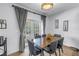 Dining room with wooden table, gray chairs, and large sliding glass doors with gray curtains at 8127 Siquita Ne Dr, St Petersburg, FL 33702