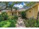Inviting front entrance with a tiled walkway, lush landscaping, and charming curb appeal with mature palms and shade trees at 8127 Siquita Ne Dr, St Petersburg, FL 33702