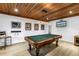 Well-lit game room with a wood plank ceiling, pool table, bar seating, and posters adorning the walls at 8127 Siquita Ne Dr, St Petersburg, FL 33702