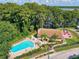 Aerial view of a community pool area with lounge chairs, picnic tables, and lake views at 860 Maclaren N Dr # A, Palm Harbor, FL 34684