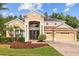 Beautiful two-story tan house with a three-car garage, manicured lawn and solar panels at 10646 Cory Lake Dr, Tampa, FL 33647