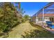 Large backyard with screened pool enclosure, lush green lawn, and landscaping; ideal for outdoor activities at 10724 Cory Lake Dr, Tampa, FL 33647