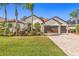 Stunning single-story home with a three-car garage, lush landscaping, and a brick-paved driveway at 10724 Cory Lake Dr, Tampa, FL 33647