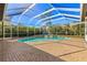 Beautiful in-ground pool inside screened lanai with brick patio and waterfall feature, surrounded by lush landscaping at 10724 Cory Lake Dr, Tampa, FL 33647