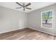 Relaxing bedroom with neutral walls, hardwood floors, a ceiling fan, and a large bright window at 11225 Flower Ave, Weeki Wachee, FL 34613
