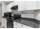 Well-appointed kitchen featuring white cabinets, dark counters, and a sleek black range oven with overhead microwave at 11225 Flower Ave, Weeki Wachee, FL 34613
