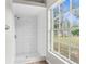 Bathroom shower with white subway tile, a rainfall shower head, and a window with a lush view at 11225 Flower Ave, Weeki Wachee, FL 34613