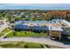Aerial view of a single-story community building with palm trees, a well-maintained lawn and ample parking at 11628 Aspenwood Dr, New Port Richey, FL 34654