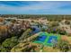 Aerial view of two blue and green tennis courts alongside a pond surrounded by mature trees and neighborhood at 11628 Aspenwood Dr, New Port Richey, FL 34654