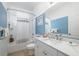 Bright bathroom features a shower-tub combo, white vanity, and blue accent wall at 11813 Crawford Parrish Ln, Parrish, FL 34219