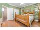Green-walled bedroom with a wooden bed frame, laminate floors, and ensuite bathroom access at 11813 Crawford Parrish Ln, Parrish, FL 34219