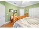 Cozy green bedroom showcasing a wooden bed frame, hardwood floors, and a mirror at 11813 Crawford Parrish Ln, Parrish, FL 34219