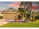 Inviting yellow house showcasing a well-maintained lawn, brick driveway, and mature palm trees, creating a warm curb appeal at 11813 Crawford Parrish Ln, Parrish, FL 34219