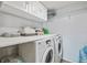 Bright laundry room features a washer, dryer, overhead cabinets, and shelving for organized storage at 12102 Steppingstone Blvd, Tampa, FL 33635
