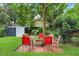 Landscaped backyard featuring a fire pit area with red chairs and a shed at 1213 E Idlewild Ave, Tampa, FL 33604