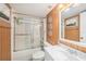 Bathroom with wood paneled walls, framed mirror, white vanity, and enclosed shower/tub at 14900 Gulf Blvd # 308, Madeira Beach, FL 33708