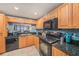 Well-equipped kitchen with black appliances, wood cabinets, granite countertops, and an open view to the dining area at 14900 Gulf Blvd # 308, Madeira Beach, FL 33708