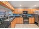 Kitchen featuring wood cabinets, black appliances, granite counters, and an open view of the living area at 14900 Gulf Blvd # 308, Madeira Beach, FL 33708
