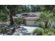 A single-story home with tropical landscaping, an attached garage and mature trees at 1613 Long Pond Dr, Valrico, FL 33594