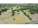 Aerial view of a grand estate with a long driveway, expansive lawn, and surrounded by lush greenery at 17566 Hyland Ln, Dade City, FL 33523