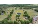Aerial view of a newly built estate with a sprawling green lawn surrounded by woods and neighboring properties at 17566 Hyland Ln, Dade City, FL 33523