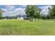 Wide backyard with modern white home, screened porch, manicured lawn, and mature trees at 17566 Hyland Ln, Dade City, FL 33523
