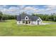 Beautiful modern farmhouse with a covered porch, black trim, white siding, and green lawn at 17566 Hyland Ln, Dade City, FL 33523