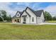 Side view of modern farmhouse, black trim, white siding, garage, and expansive green lawn at 17566 Hyland Ln, Dade City, FL 33523