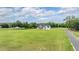 Expansive green lawn with a modern farmhouse featuring covered porch, black trim, and white siding at 17566 Hyland Ln, Dade City, FL 33523