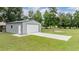 A detached gray metal garage with white door and concrete driveway in a grassy, tree-filled landscape at 17566 Hyland Ln, Dade City, FL 33523
