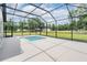 A serene pool set within a screened lanai, offering views of the expansive backyard at 17566 Hyland Ln, Dade City, FL 33523