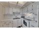 Bright kitchen featuring white appliances, cabinetry, and a stainless steel double sink basin at 1802 Bedford Ter # 185, Sun City Center, FL 33573