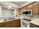 Kitchen with stainless sink and white appliances and wood cabinetry at 1813 Lakeview Dr, Brandon, FL 33511