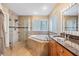 Bright bathroom features a soaking tub, glass shower, and a granite-topped vanity with wood cabinetry at 2016 Chelam Way, Brandon, FL 33511