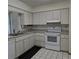 Traditional kitchen featuring light-colored cabinets, white appliances, and black-and-white tile flooring at 2226 Giralda Ave, Spring Hill, FL 34606