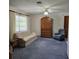 Living room with plush blue carpet, a large window, and an ornate wooden armoire at 2226 Giralda Ave, Spring Hill, FL 34606