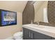 Stylish half bathroom with a patterned accent wall, dark blue vanity, and ample lighting at 2902 W Fair Oaks Ave, Tampa, FL 33611