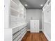 Bright walk-in closet with custom white cabinetry, drawers, shelves, and wooden floors for organized storage at 2902 W Fair Oaks Ave, Tampa, FL 33611