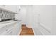 Bright hallway with hardwood floors, white cabinets, a black and white tiled backsplash, and ample storage space at 2902 W Fair Oaks Ave, Tampa, FL 33611