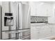 Modern kitchen featuring stainless steel refrigerator, white cabinets, and a marble countertop with mosaic backsplash at 2902 W Fair Oaks Ave, Tampa, FL 33611
