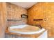 A bathroom with a whirlpool tub, neutral tile surround, and a decorative faucet and shelves at 2969 La Concha Dr, Clearwater, FL 33762