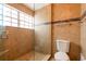 Bathroom featuring glass enclosed shower, earth-toned tile, and adjacent toilet at 2969 La Concha Dr, Clearwater, FL 33762
