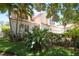 Charming two-story home with a terra cotta roof, lush landscaping, and an attached white garage at 2969 La Concha Dr, Clearwater, FL 33762