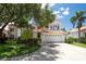 Charming two-story home with terra cotta roof, a manicured lawn, mature trees, and a white, six-panel garage door at 2969 La Concha Dr, Clearwater, FL 33762