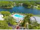 Aerial view of community pool, parking, and a glimpse of the adjacent lake at 3114 Lake Pine Way # G1, Tarpon Springs, FL 34688