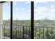 A balcony view overlooks lush greenery, city buildings, and a bright blue sky filled with fluffy white clouds at 3211 W Swann Avenue # 707, Tampa, FL 33609